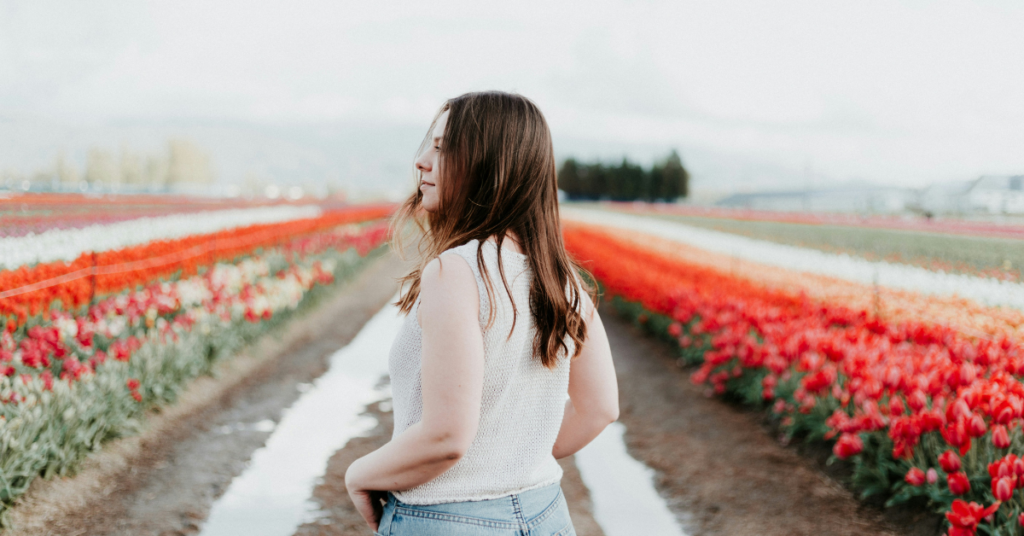 young woman with brown hair standing alone in a tulip field