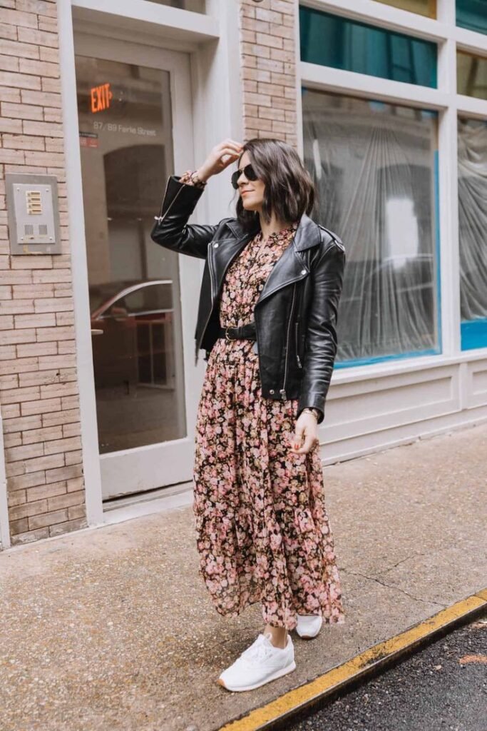 Woman with short hair wearing a floral maxi dress and black leather jacket as a fall transition outfit idea