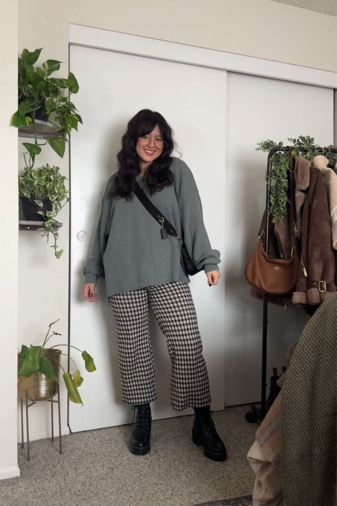 Brunette woman in checker patterned pants with black boots and an oversized sweater for a comfy fall outfit