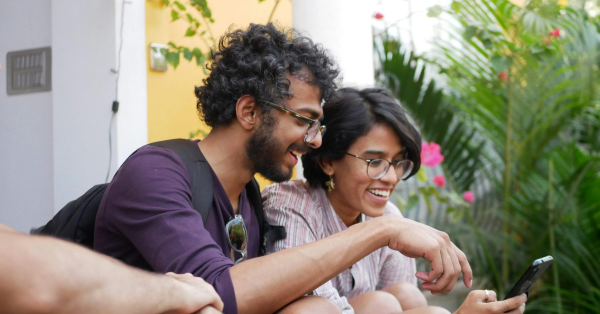 Young ethnic couple laughing and looking at a dating app