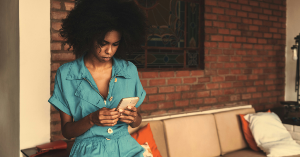 Beautiful Black woman looking sadly at cellphone and experiencing dating app burnout