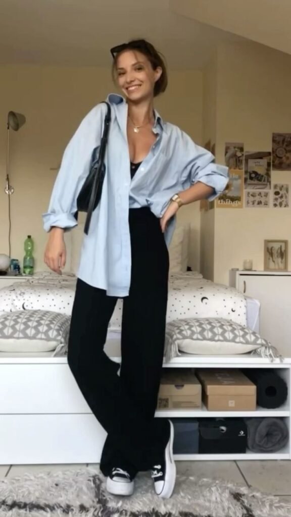 Woman wearing a half tuck button down shirt and black pants for a fall transition outfit